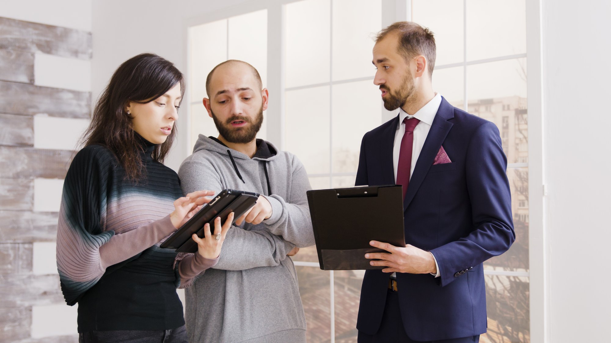 real-estate-agent-talking-with-couple-and-holding-2025-02-19-19-24-29-utc